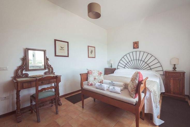 Camera semplice con elementi in legno e dettagli rustici, perfetta per un soggiorno sereno in campagna.