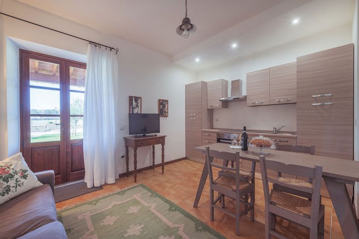 Soggiorno semplice e funzionale in agriturismo, dotato di una cucina operativa, ideale per rilassarsi a contatto con la natura.
