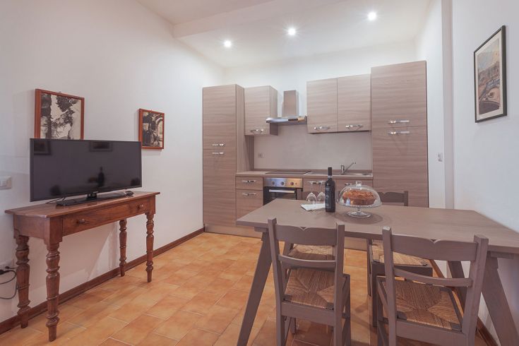 Spazioso soggiorno con angolo cottura, dotato di tavolo e televisore. Ideale per momenti di relax.