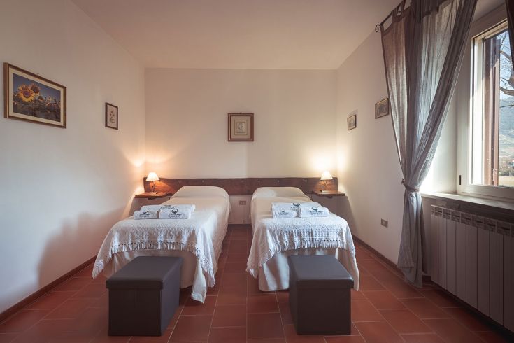 Camera semplice con letti singoli all'interno di un agriturismo circondato dalla natura.