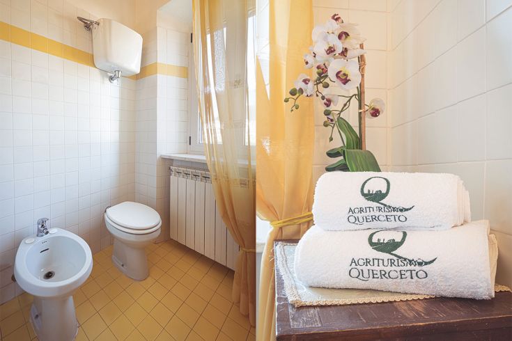 Bagno in agriturismo con teli bianchi e un elemento di natura rappresentato da un'orchidea.