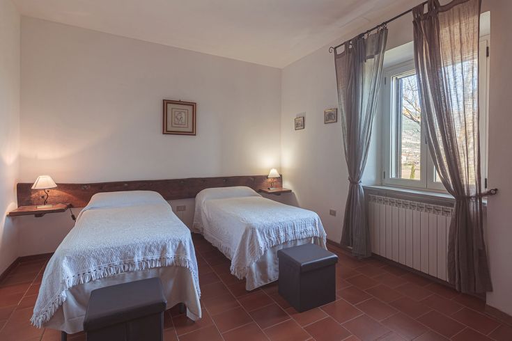 Camera semplice con due letti singoli, perfetta per riposarsi in un ambiente rurale.