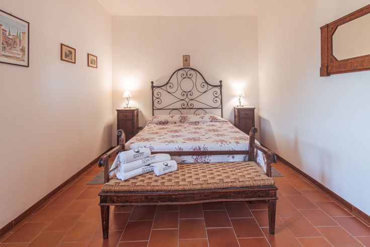 Camera semplice con letto matrimoniale e arredi tradizionali, ideale per un soggiorno tranquillo.