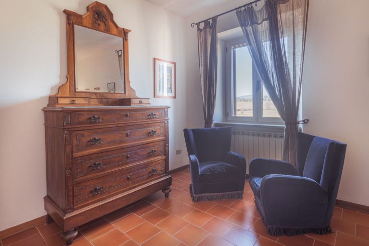 Una stanza semplice e confortevole con un mobile in legno e poltrone blu, perfetta per momenti di relax.