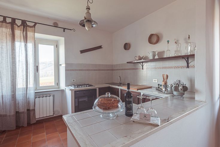 Cucina ampia e luminosa con affaccio sul paesaggio umbro, caratterizzata da elementi rustici e dettagli accoglienti.