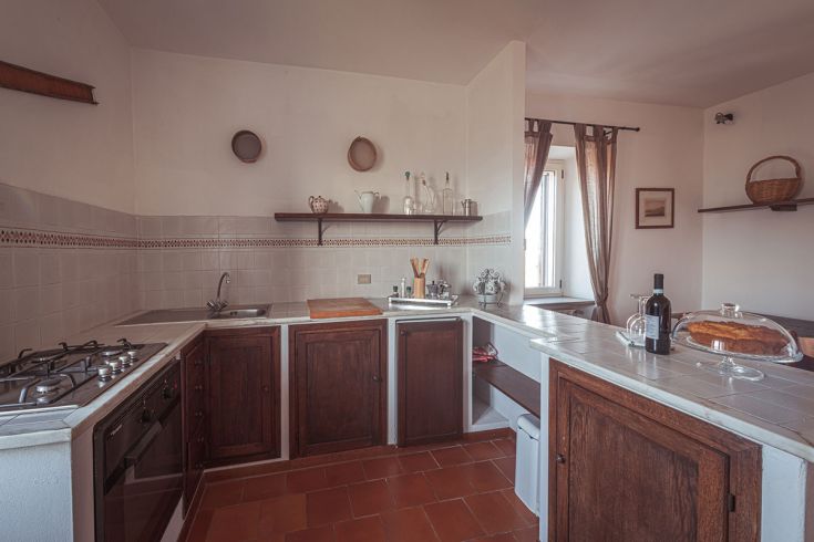 Cucina spaziosa e ben illuminata, arredata con elementi in legno, ideale per i piatti tradizionali.