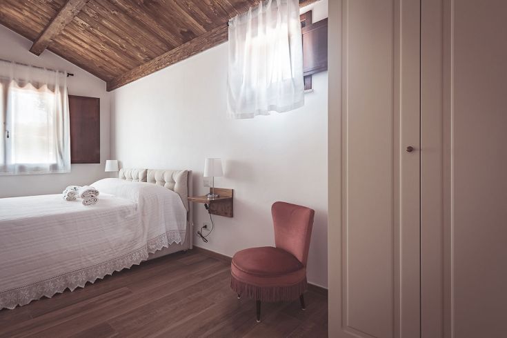 Camera semplice con letto matrimoniale, arredamento in legno e una vista sui dintorni naturali.