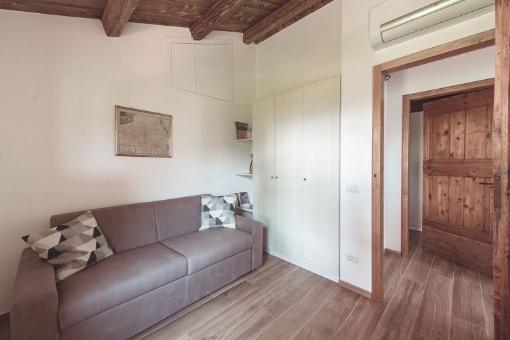 Un soggiorno accogliente con divano e cuscini a motivi geometrici. La stanza è ben illuminata e presenta arredi in legno.