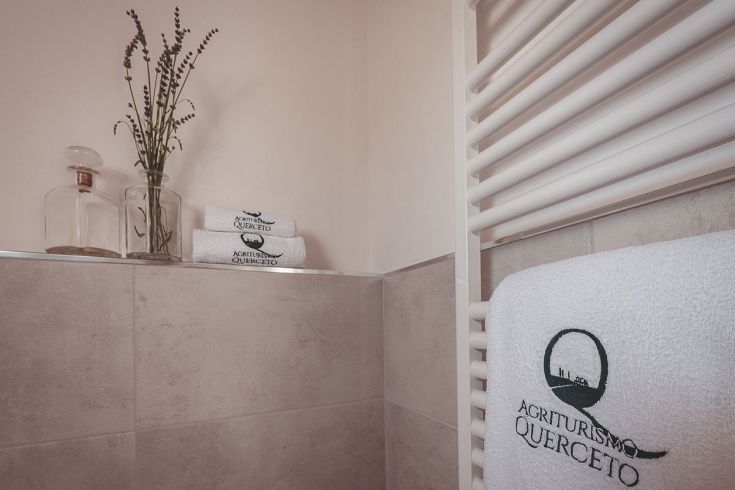 Accogliente ambiente all'Agriturismo Querceto, con asciugamani bianchi e decorazioni semplici in stile naturale.