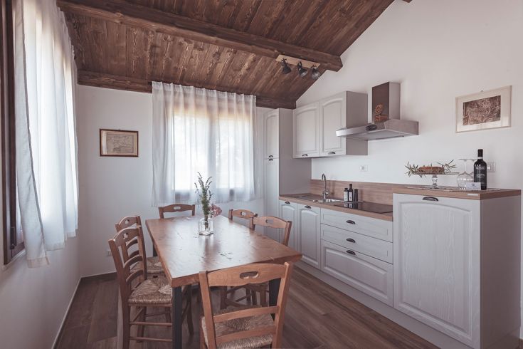 Cucina calda e confortevole con un tavolo in legno e ampie finestre, perfetta per incontri tra amici e familiari.