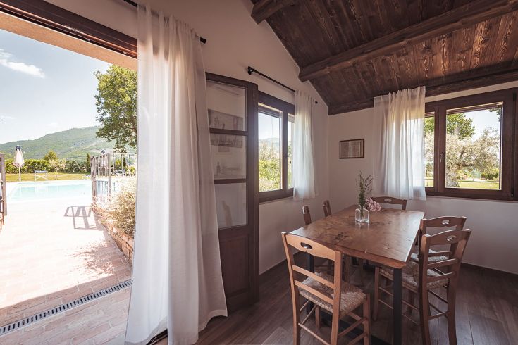 Interno semplice e accogliente con panorama sulla piscina e le colline circostanti.