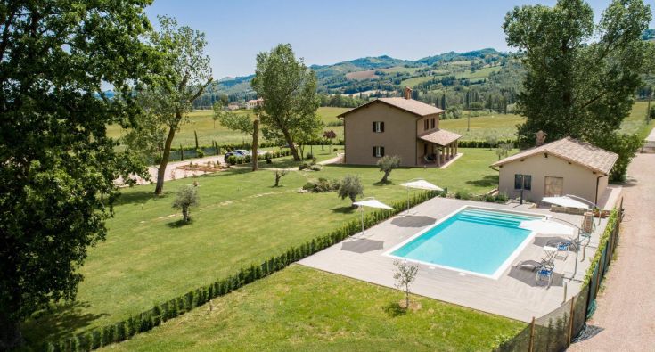 Scena dell'agriturismo con piscina, circondato da un ambiente naturale tipico dell'Umbria.