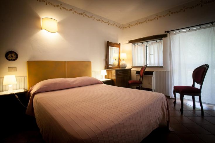 Simple and well-lit bedroom featuring a double bed and rustic style furniture.