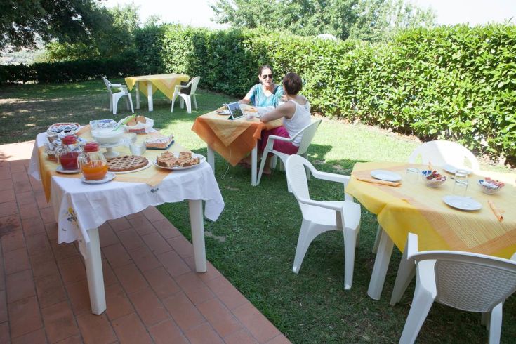 Outdoor breakfast in a peaceful garden with friends, surrounded by plants and flowers.