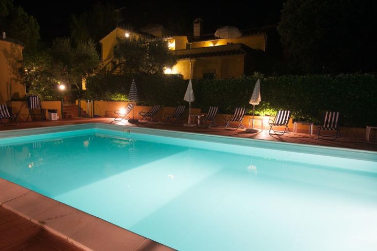 A serene evening scene featuring a lit swimming pool, perfect for a relaxing night.