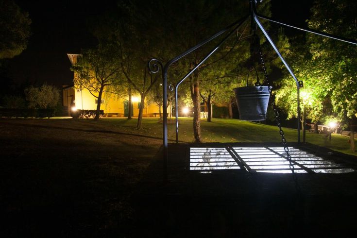 A rustic building surrounded by greenery, illuminated by moonlight and trees, with light spots through the leaves.
