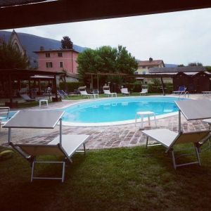 Piscina spaziosa immersa nel verde, attrezzata con lettini per il relax, in un ambiente tranquillo di campagna.