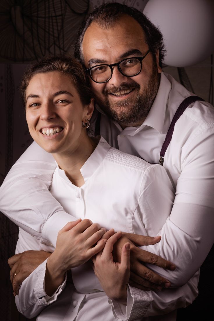 Una coppia sorridente si abbraccia in un ambiente accogliente e confortevole, con uno sfondo curato.