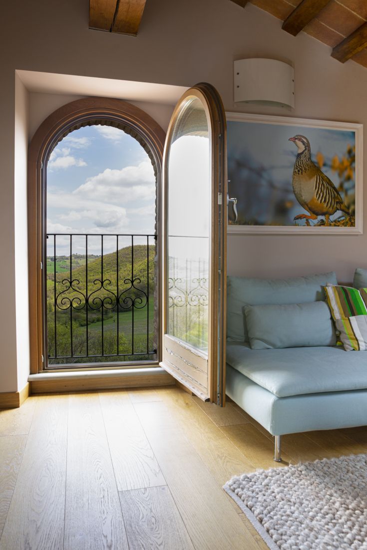 Panorama da un soggiorno con porta ad arco aperta. Natura e comfort si incontrano in un ambiente tranquillo.