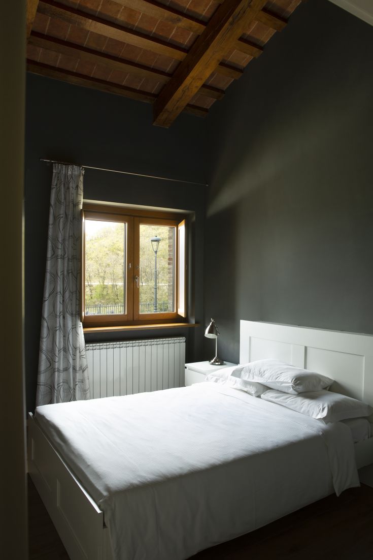 Camera con letto matrimoniale e panorama su un paesaggio verde. Atmosfera rilassata e accogliente.