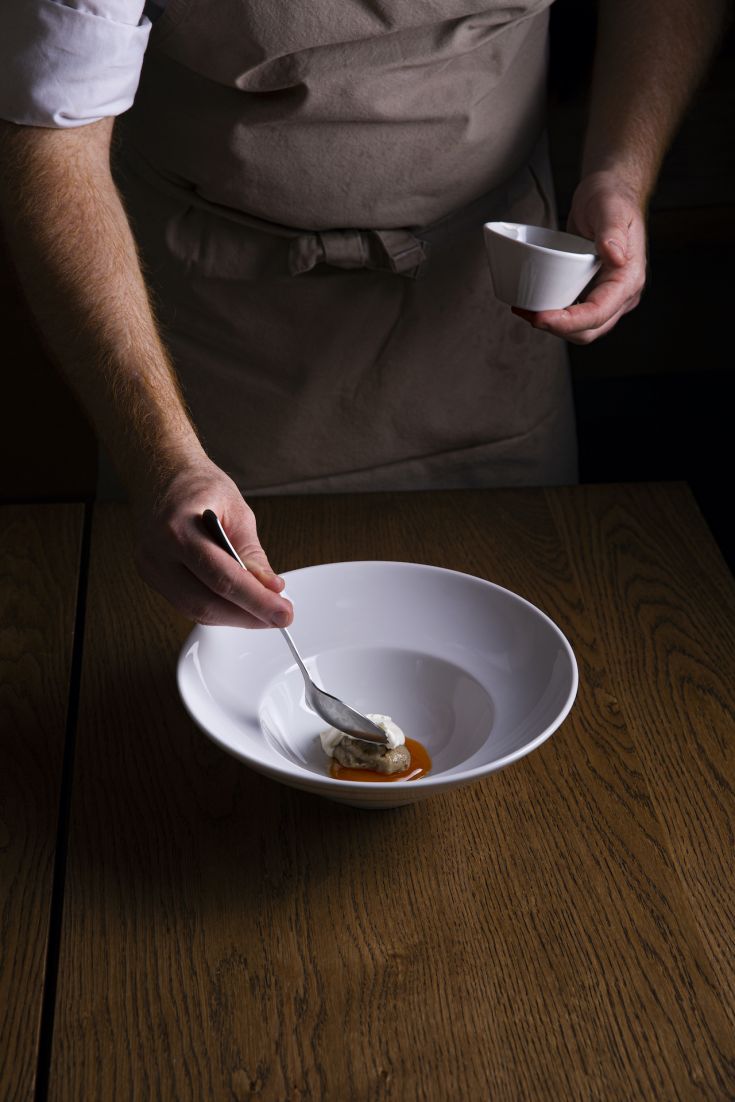 Un cuoco mentre sistema con attenzione un piatto di alta cucina.