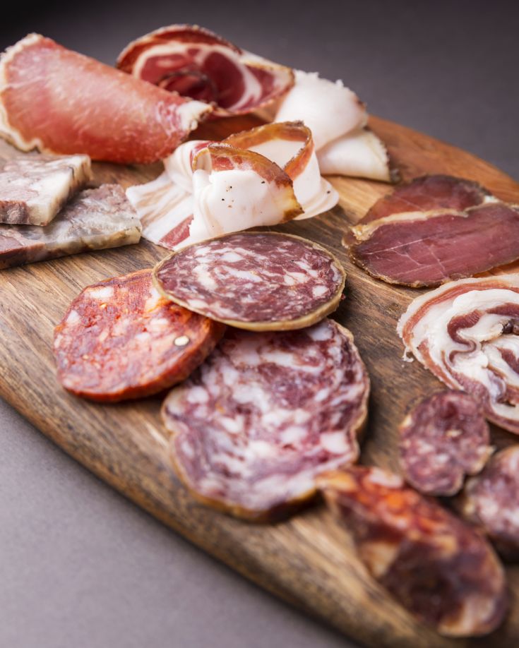Un tagliere con una selezione di salumi, presentati con varietà di colori e forme.