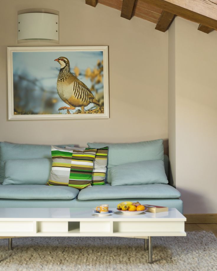 Un soggiorno arredato con un divano azzurro e cuscini a righe, caratterizzato da un tavolino e luci soffuse.