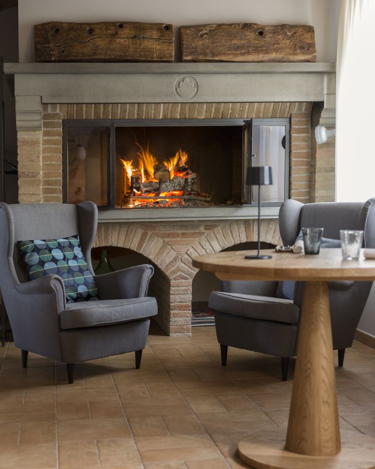 Un soggiorno accogliente con un camino acceso e poltrone grigie comode.
