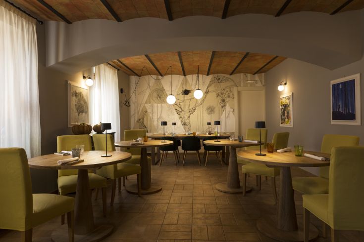 Uno spazio contemporaneo con tavoli tondi e sedie gialle, adatto per una cena tranquilla.