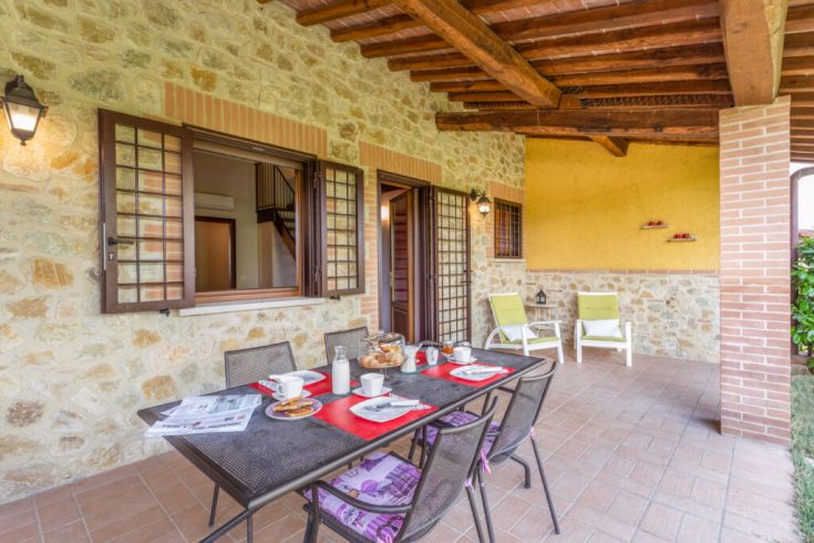 Gemütlicher Außenbereich mit einem Frühstückstisch unter dem Portikus. Perfekt für Entspannungsmomente.