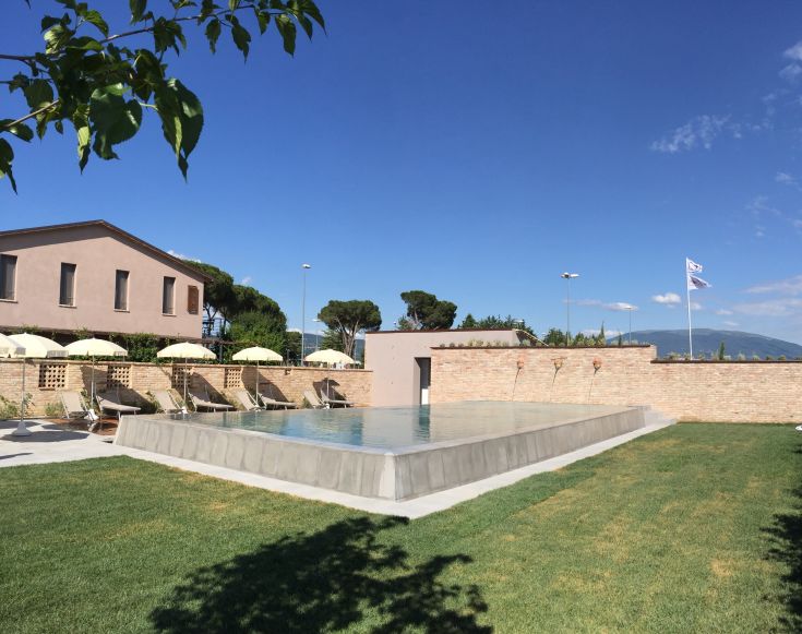 Un ambiente tranquillo con piscina all'aperto circondata da aree verdi.