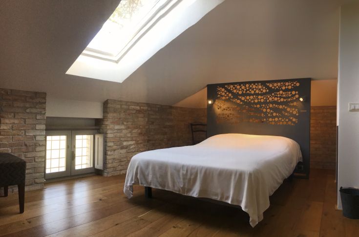 Una stanza confortevole con travi a vista, luce moderna e finestre spaziose. Un angolo adatto al relax.