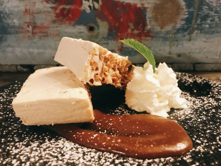 Dessert con crema, noccioline e salsa al caramello, guarnito con panna montata.