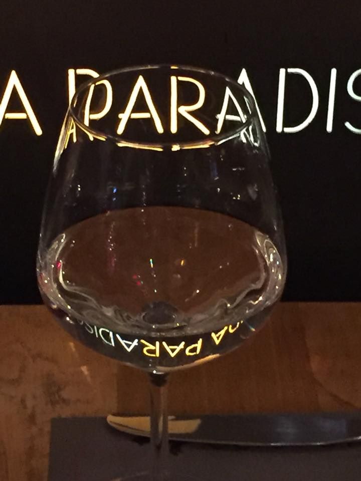 Un bicchiere d'acqua mostra il logo illuminato del locale, offrendo un effetto visivo interessante.