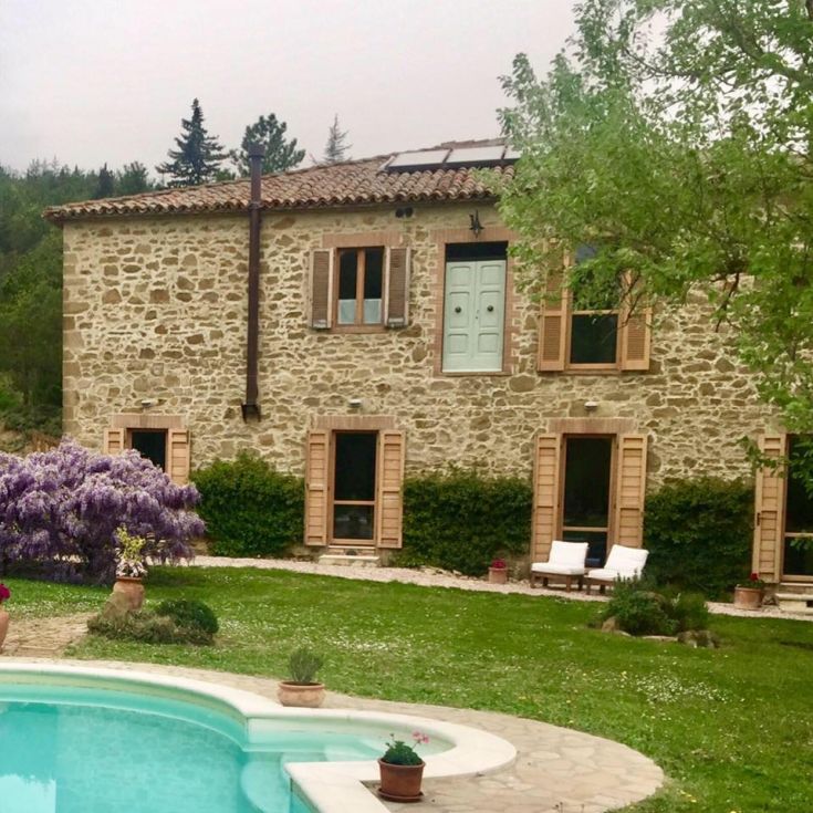 A stone house located among the Umbrian hills, featuring a swimming pool and well-kept green spaces.