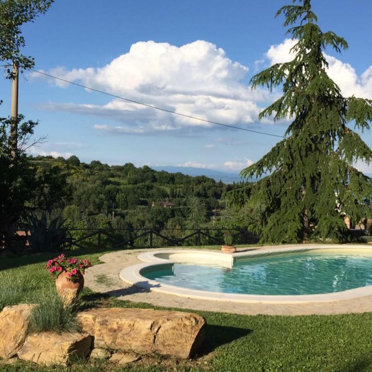 A pool surrounded by greenery, nestled among the Umbrian hills under a serene sky, perfect for relaxation.