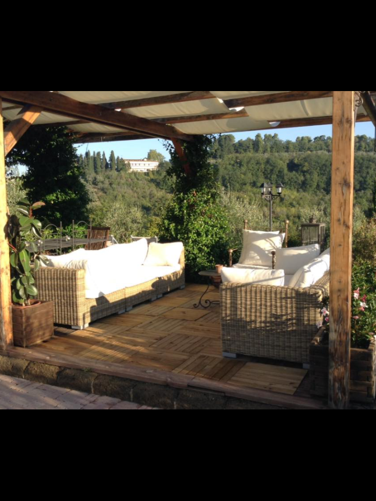 A pleasant outdoor space with rattan sofas, surrounded by a lush green landscape.