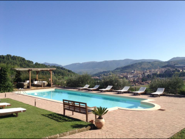 A pool located in a natural setting, surrounded by hills and a green landscape.