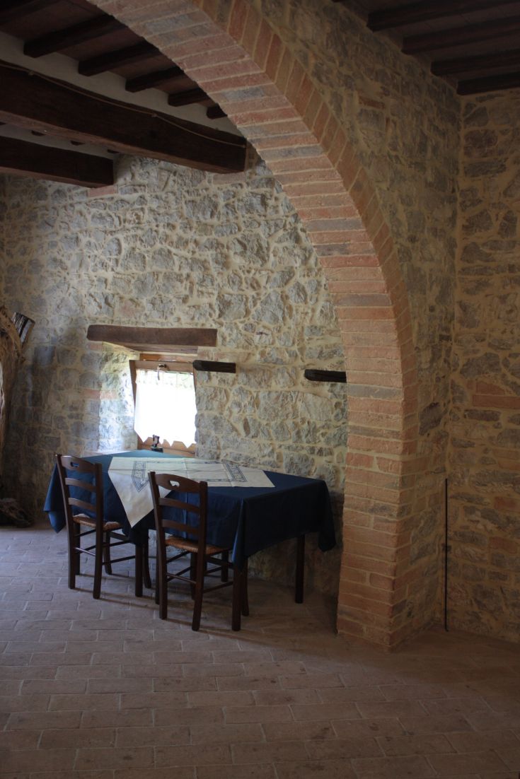 A simple corner of an agriturismo with a table and chairs on a terracotta floor.