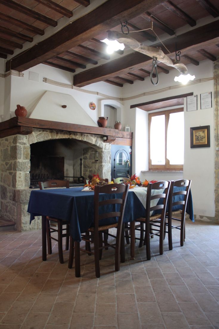 A dining room with a set table and a stone fireplace, featuring simple and pleasant decor.