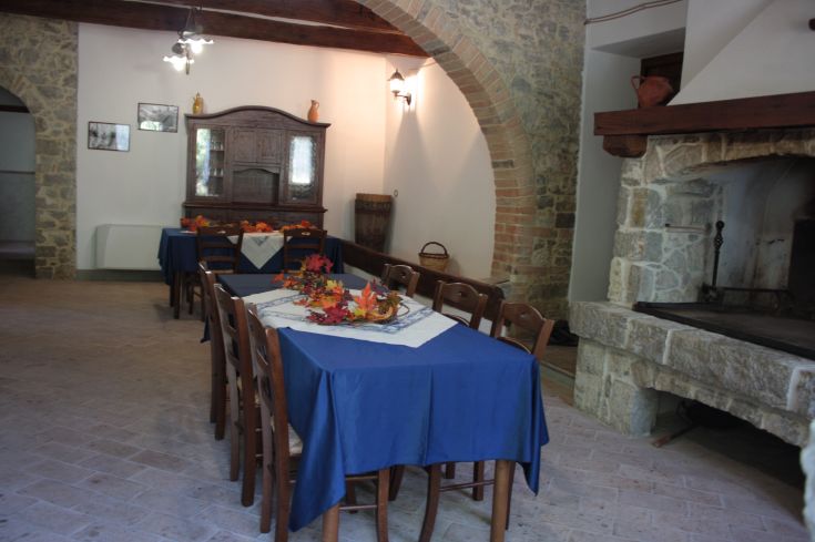 A simple dining room in a farmhouse with arranged tables and visible natural elements.
