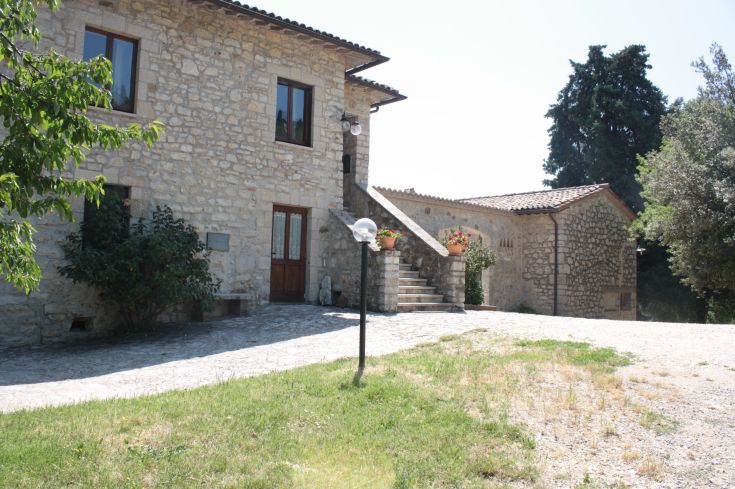 Stone farmhouse located amidst typical Umbrian vegetation.