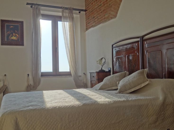 Une chambre simple et accueillante, inondée de lumière naturelle et avec des éléments de mobilier traditionnels.