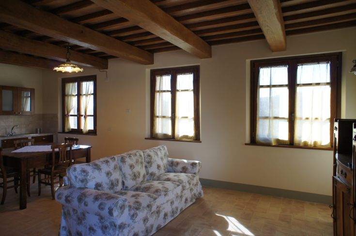 Cozy living room with wooden ceiling, bright lighting, and simple, comfortable furnishings.