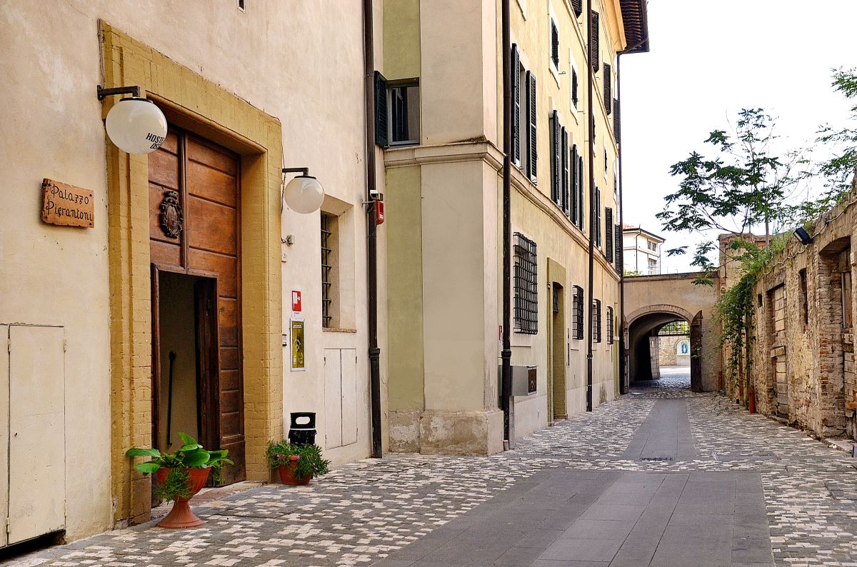 Una strada quieta con l'ingresso del Palazzo Pierantoni, un edificio storico che ospita un ostello.