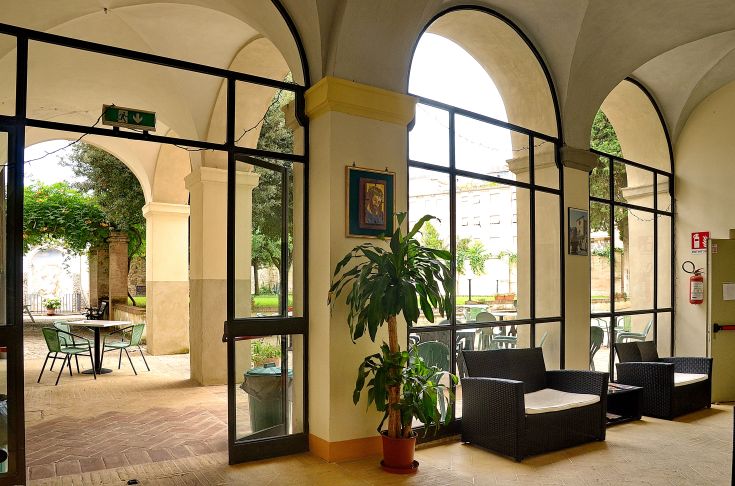 Innenraum des Ostello Pierantoni mit praktischen Möbeln und Blick auf den Garten.