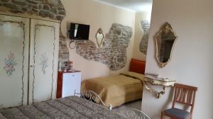 Une chambre confortable avec des détails vintage et des murs en pierre, créant une ambiance chaleureuse.