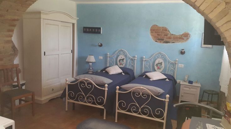 Chambre simple avec lits simples et murs bleus, équipée de meubles fonctionnels et confortables.