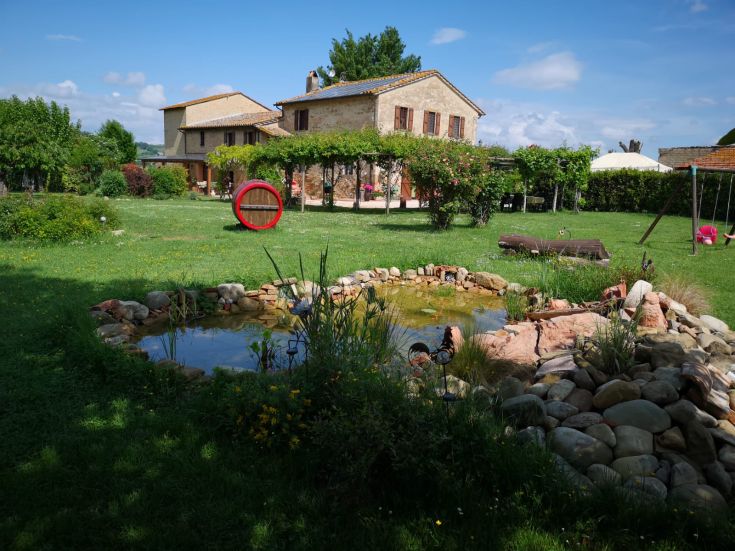 Un jardin soigné et une maison de style rustique, entourés d'un paysage vert près d'un lac.