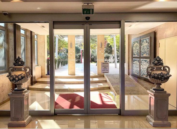 Entrée simple d'un bâtiment avec des plantes et des decorations murales.